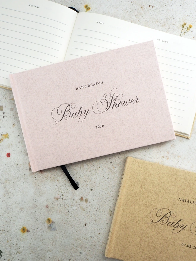 Personalised Baby Shower book. A linen embossed hardcover book with baby shower across the middle in a calligraphy font. The book is the personalised with text at the top and text at the bottom of the book.