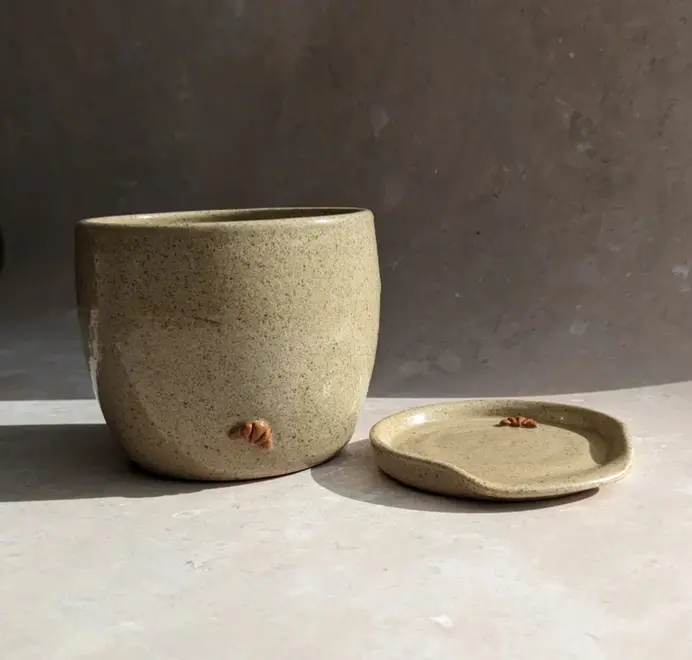 Biscuit colored croissant coffee cup with a subtle croissant design, placed against a grey marble background.