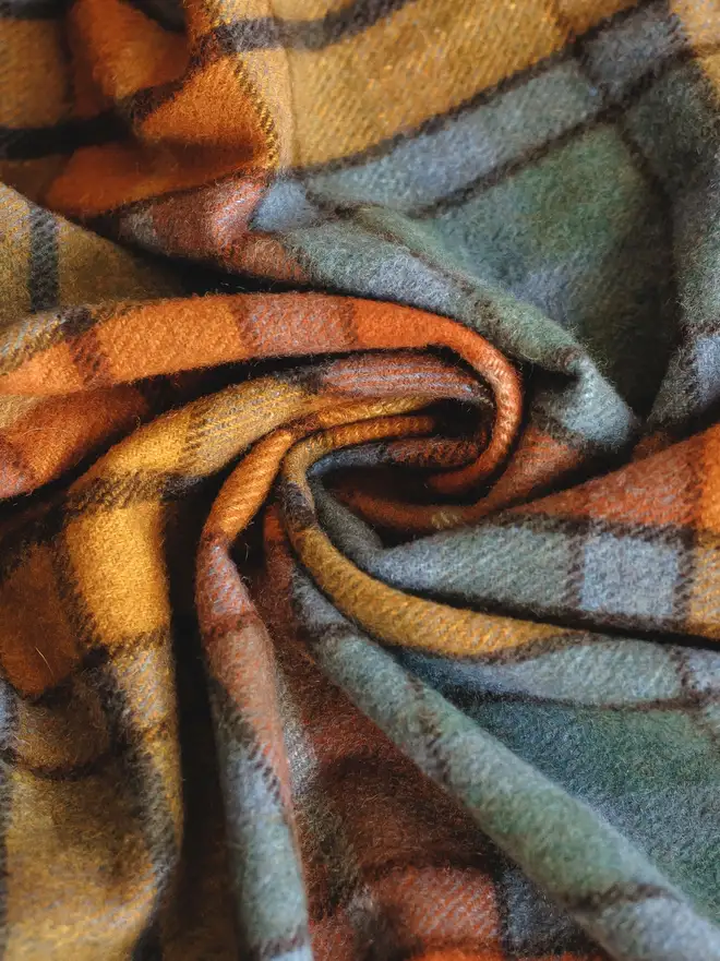 Buchanan Antique Picnic Blanket, a colourful picnic blanket curled up. 