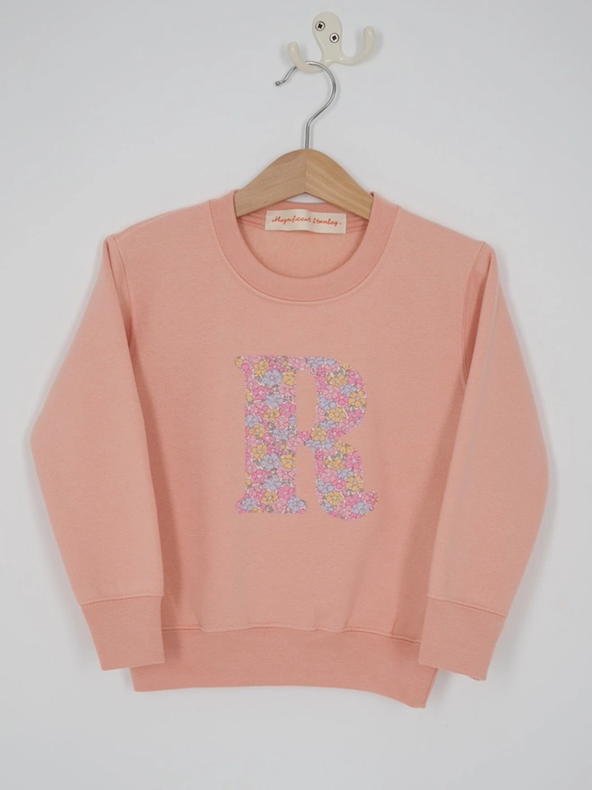 a personalised dusty pink sweatshirt with her initial sewn on the front in floral liberty print 
