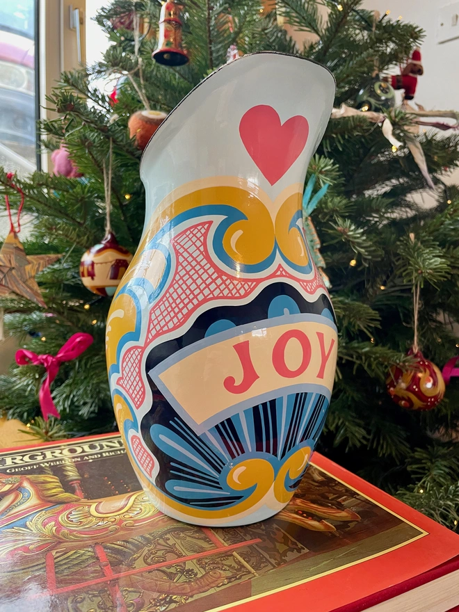 Blue enamel jug hand painted with a fairground design in blue, pink and yellow