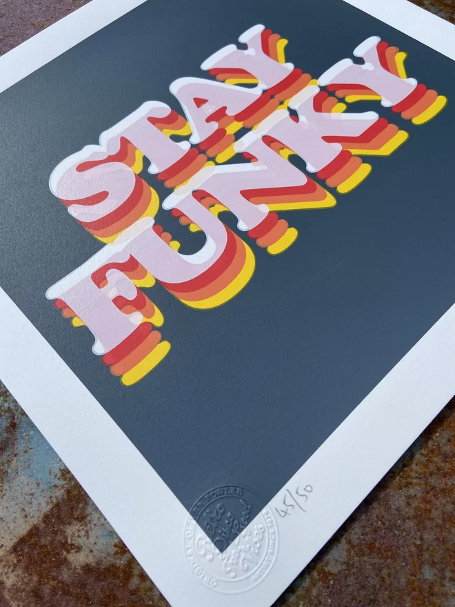 "Stay Funky" Hand Pulled Screen Print square with grey background and the words stay funky printed on top in retro letters in shadings of orange yellow and red 