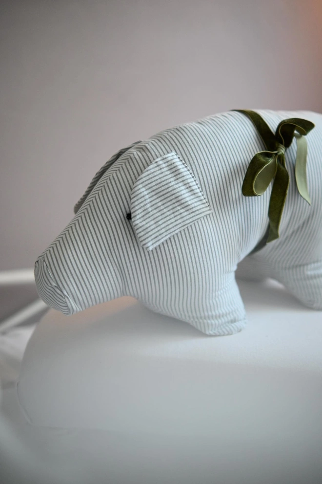 Cotton Pig Plushie, a cotton pig plushie sitting on a decorated bed. 