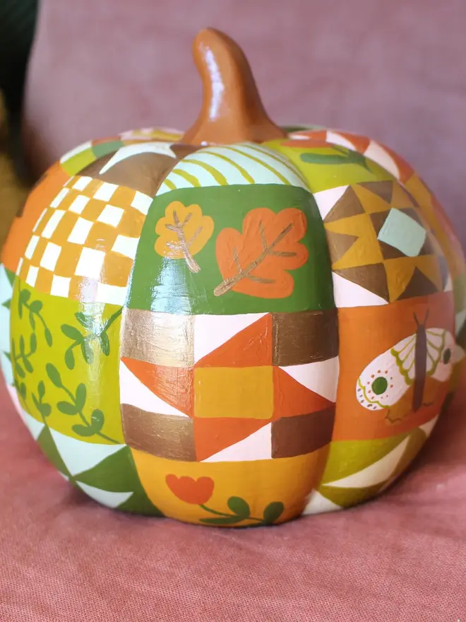 hand-painted woodland ceramic pumpkin. a ceramic pumpkin painted with patchwork colours and patters, alongside mushrooms, moons, stars and flowers.