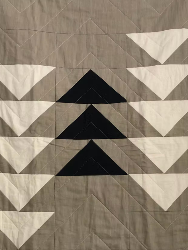 Flow Taupe Linen Throw Quilt. A quilt with a triangle pattern.