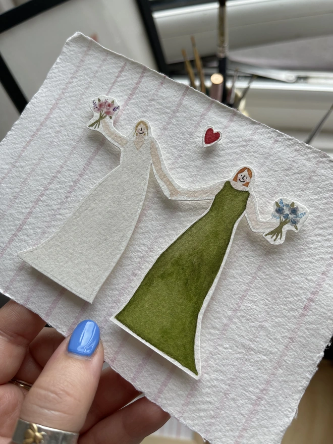 a illustration of a bride and bridesmaid holding hands and each holding a bouquet of flowers. mounted onto handmade paper as an A6 gift