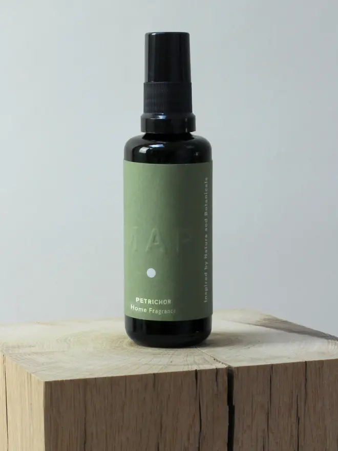 petrichor earthy home fragrance spray. spray bottle photographed on wooden surface. 