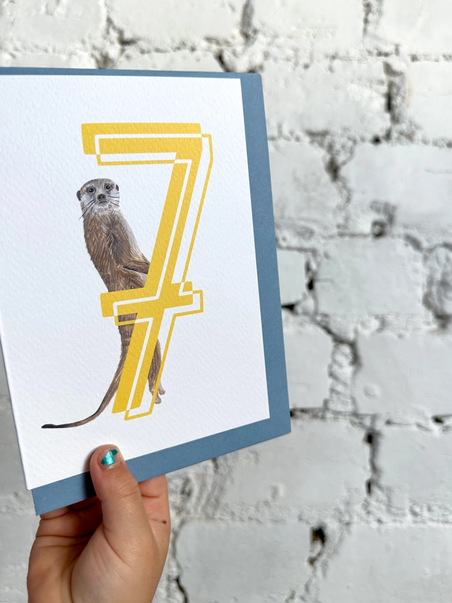 white card with a big yellow number 7 and an illustrated meerkat with a blue envelope