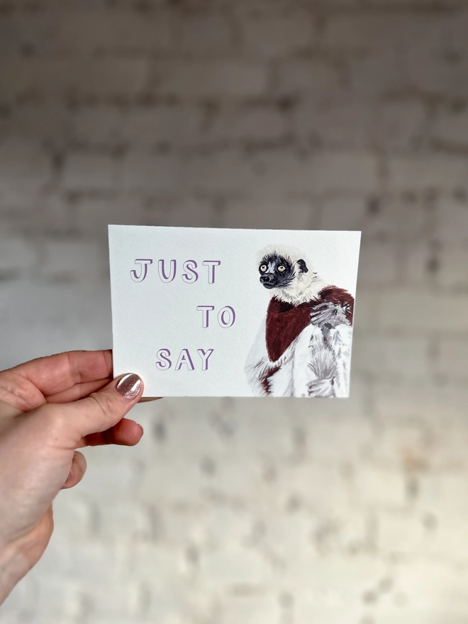  a greetings card featuring an illustration of a Coquerel’s Sifaka with the text “just to say”
