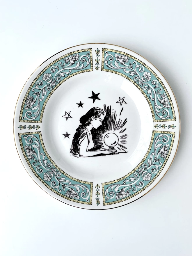 vintage plate with an ornate border, with a printed vintage illustration of a witchy fortune teller in the middle 