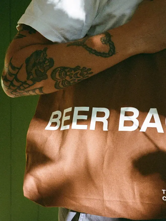 'Beer Bag' Tote Bag, worn by a man with tattoos.