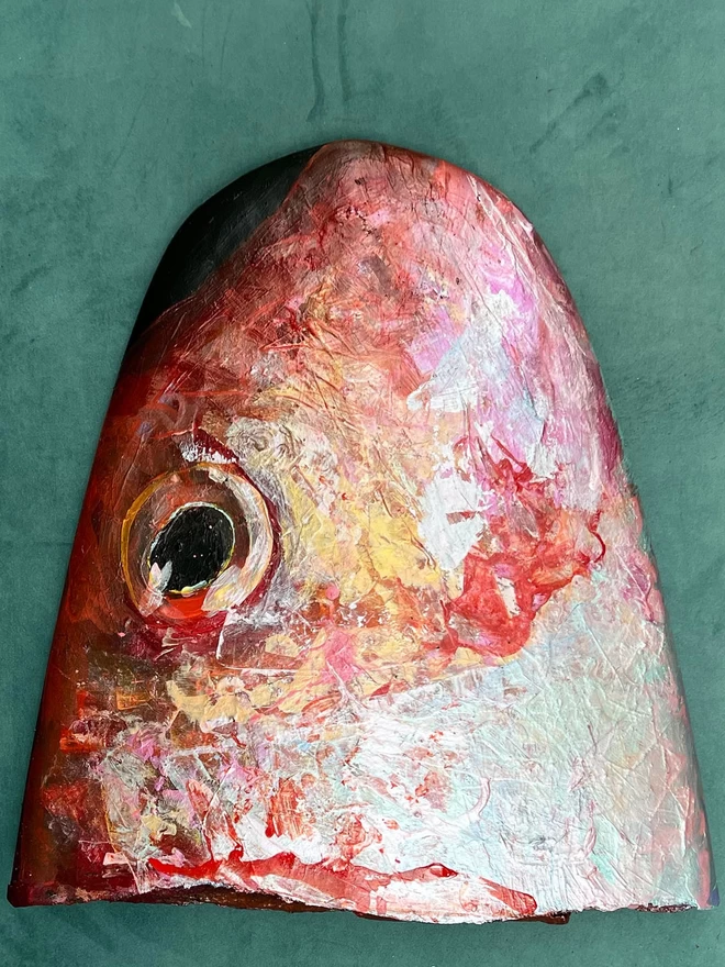 original and unique painting of the face of a red mullet fish face onto a broken, disused surfboard nose
