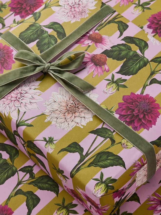 floral riot gift wrap sheet. a box wrapped in pink illustrated floral gift wrap with a green ribbon.