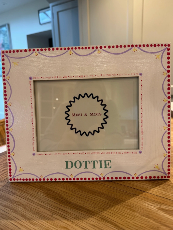 Girls’ Personalised Hand Painted White Photo Frame. A photo frame with intricate pink, white, purple and yellow designs.