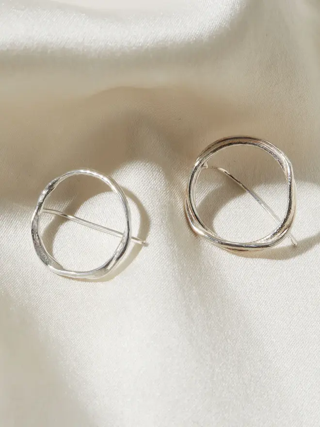 Two Silver Organic Circle Threader Earrings on a silk material