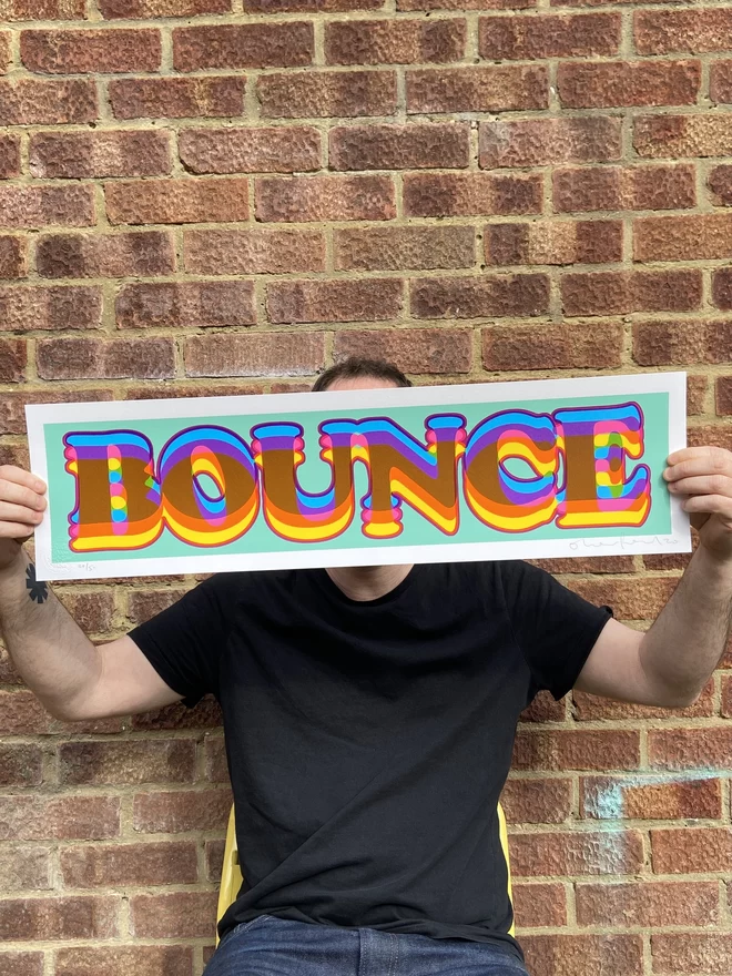 "Bounce" Hand Pulled Screen Print rectangular with green blue background and the word bounce printed on top in rainbow letters with pink outline 