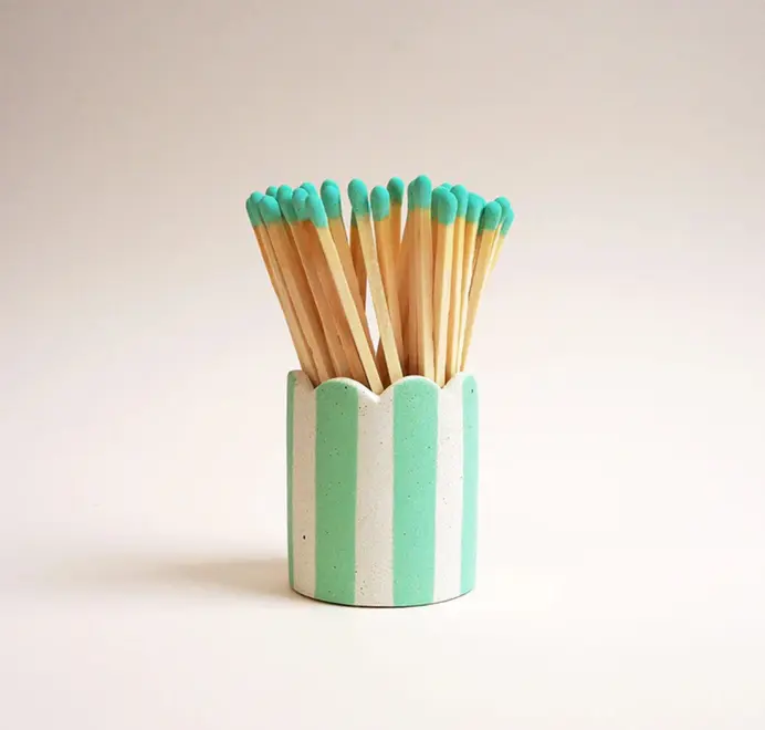 Stripy Match Stick Holders. Coloured matchsticks in a striped, scalloped matchstick holder on a white background.  