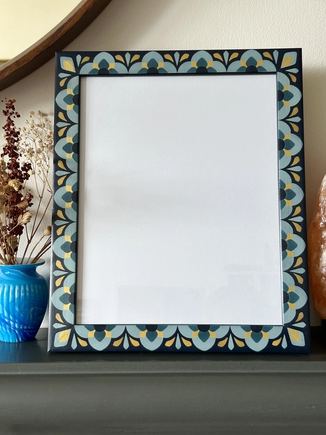 Heavily patterned medium sized picture frame hand painted in shades of blue with gold details