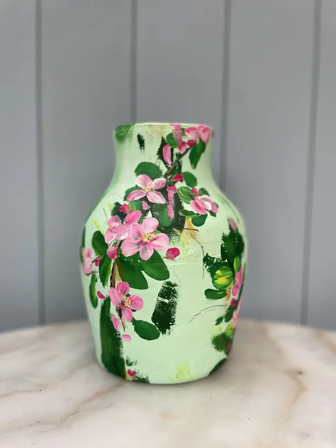 hand painted terracotta floral dried flowers vase pale green background with pink and white apple blossom flowers.