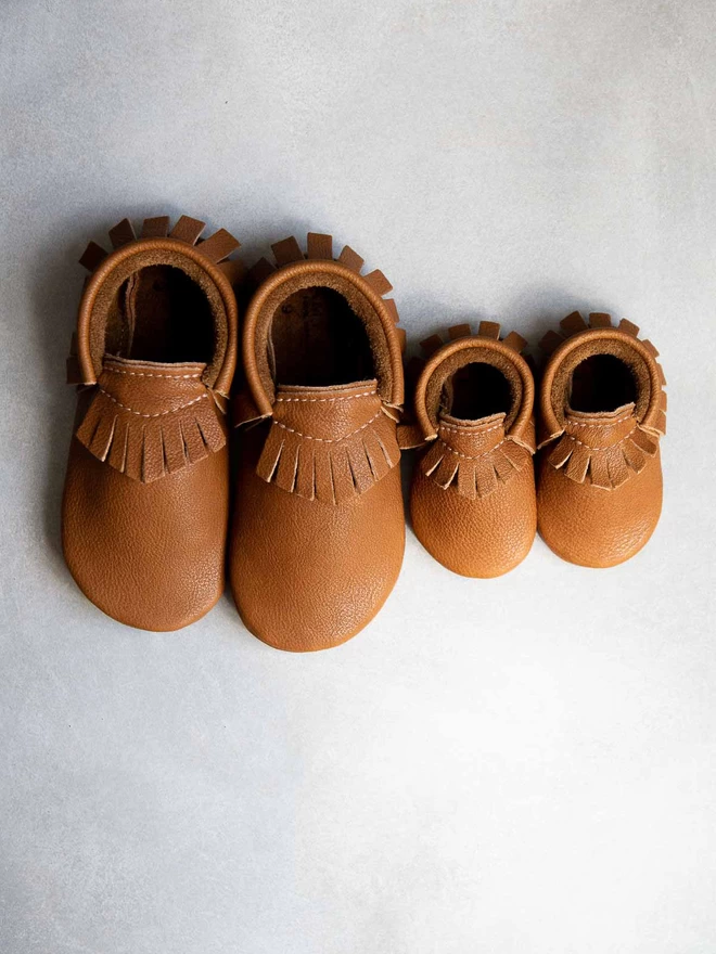 Amy and Ivor baby and toddler moccasins in classic tan colour - big moccasins next to small moccasins