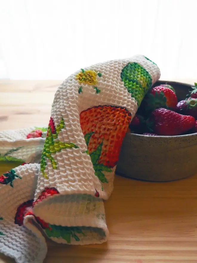 Strawberry Waffle Tea Towel, draped over a bowl of fruit. 