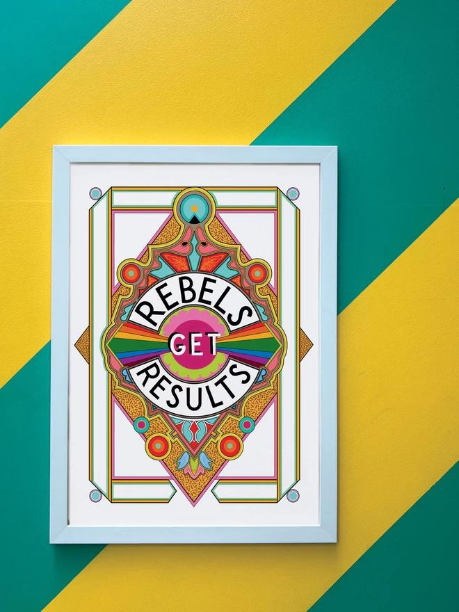Rebels Get Results is written in black on a white background at the centre of this vibrant, abstract portrait illustration, with a white background and rainbows emitting from the centre, and multi-coloured detailing. The picture is hanging in a white portrait frame against a wall painted with thick diagonal green and yellow stripes.