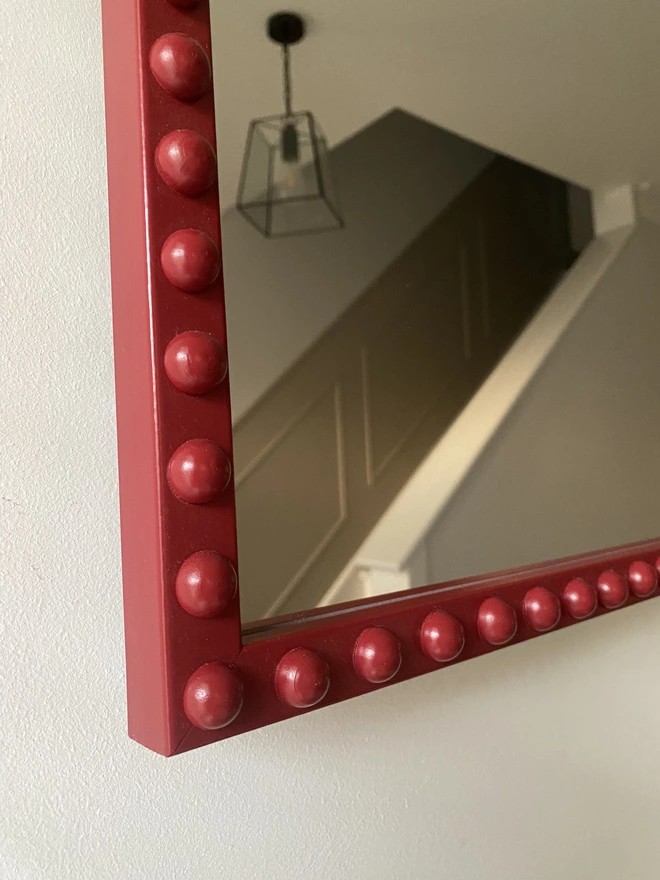 Close up of the corner of a burgundy bobbin mirror