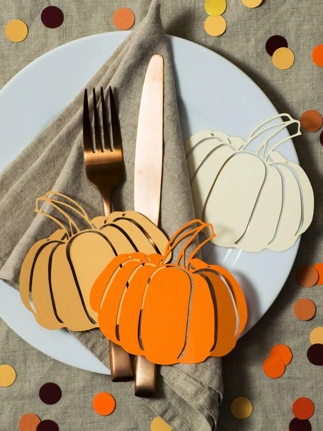 Orange, Honey and Cream Pumpkin table decorations displayed with a knife, fork and napkin, on a large white plate 