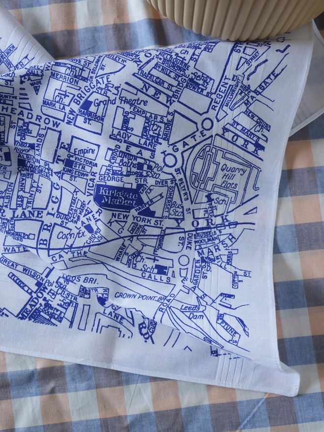 A lifestyle photo of a Mr.PS LeedsMap hankie printed in classic blue with a plant pot