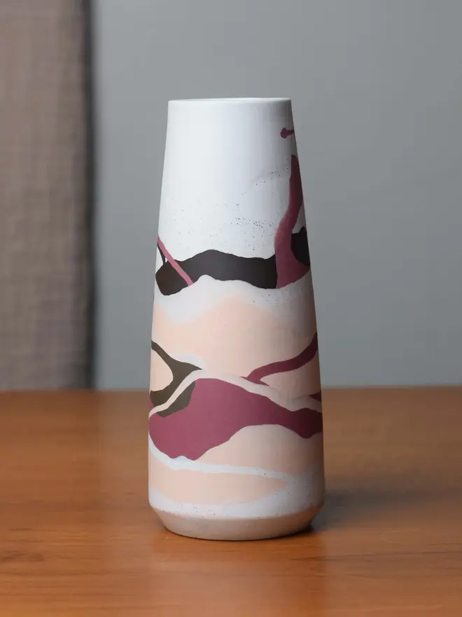 vase on wooden table, vase has streaky pattern in shades of purple, brown, and pale pink