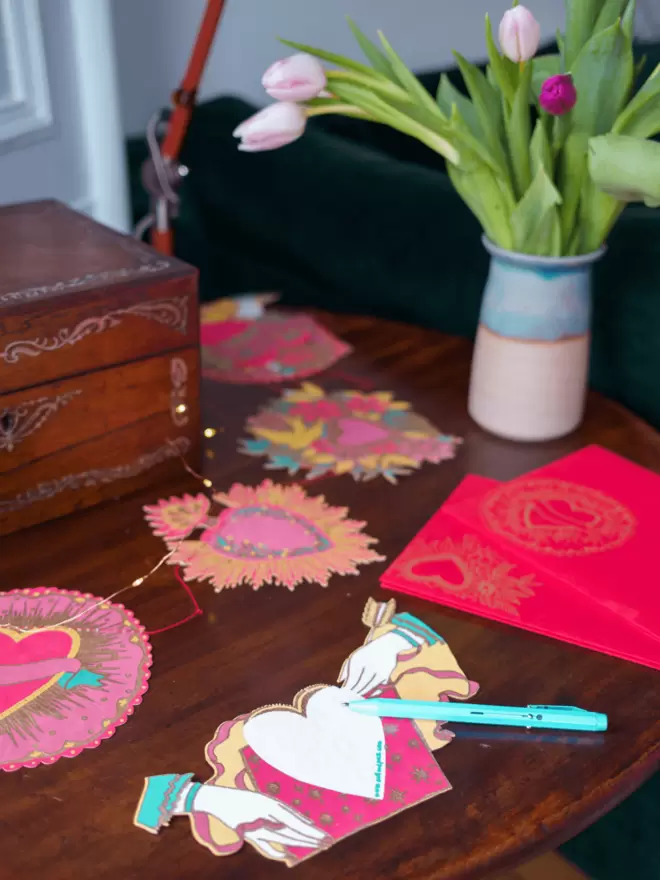 Full shot of image of greeting card and heart garland laid out on a wooden table