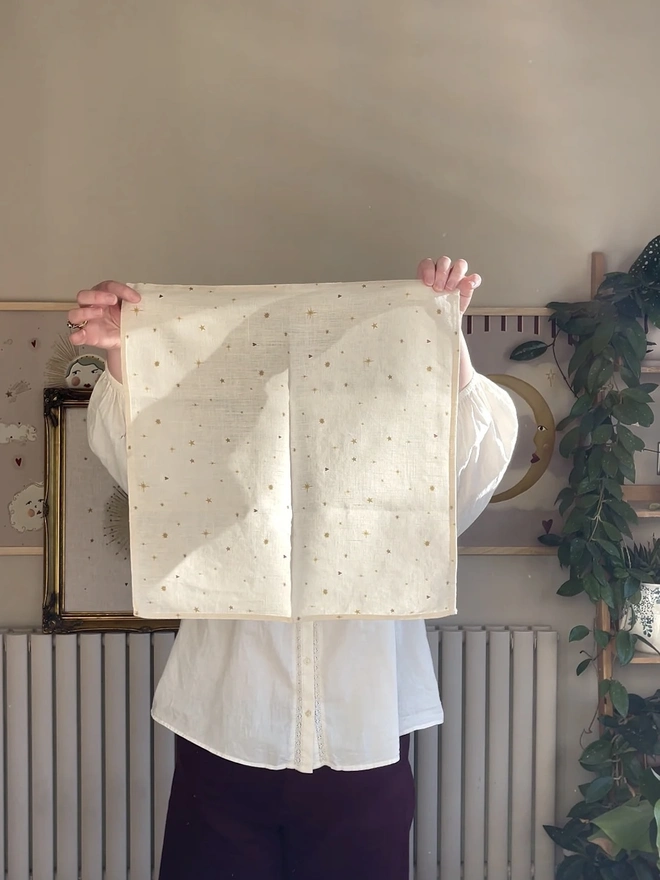 Celestial Linen Dinner Napkins (Set Of 2), a person holding a linen napkin with a sun motif. 