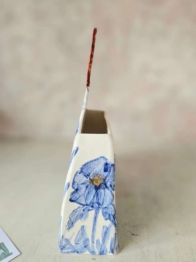 a large vase shaped like a lady with red hair looking up with blue flowers painted on her dress, side view