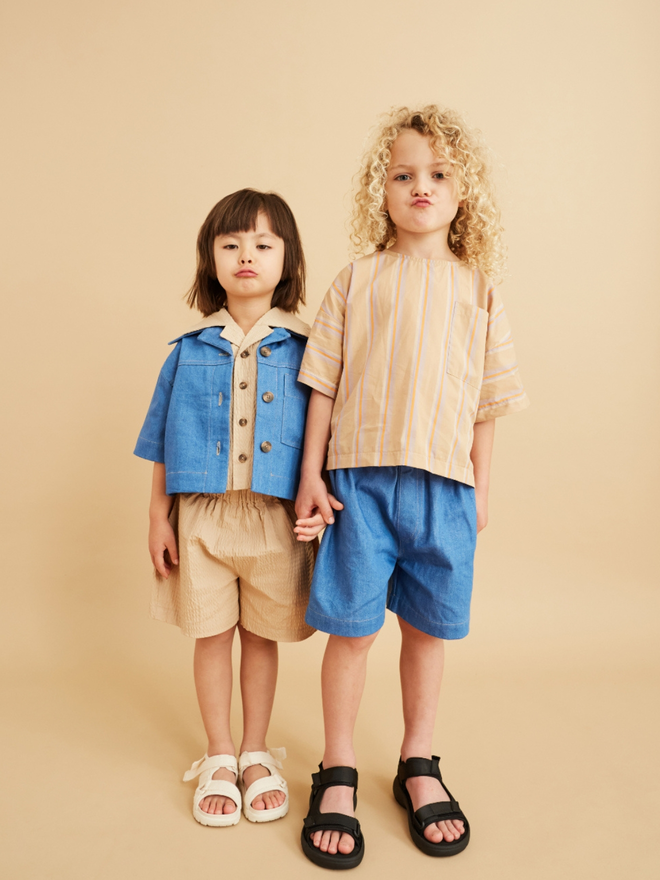 two children dressed in denim and beige looking very cool. 