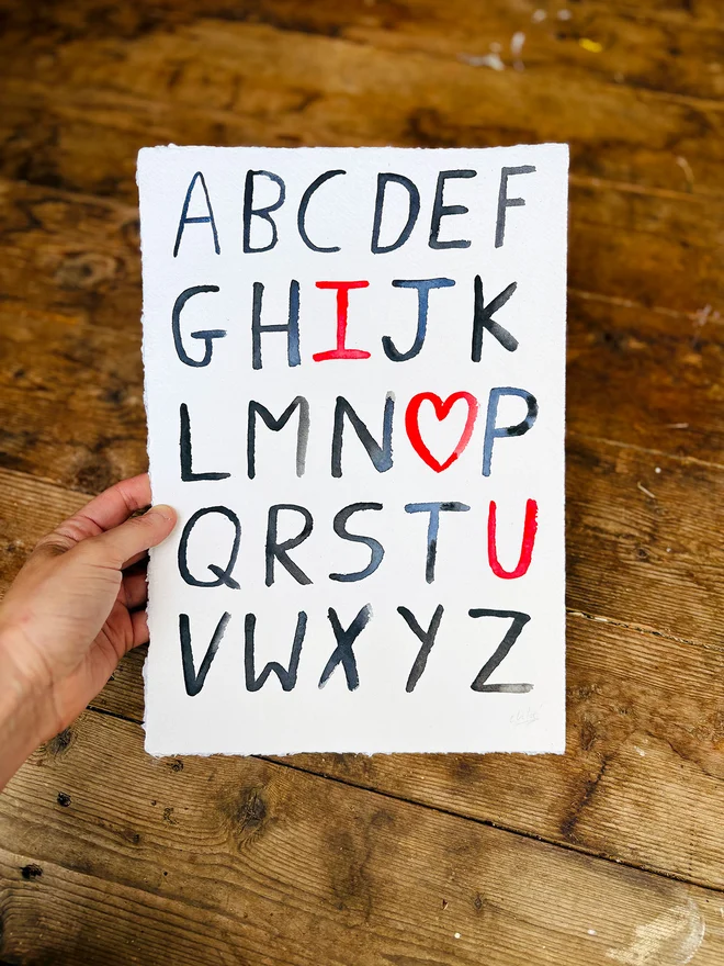 Handwritten alphabet 'I ❤️ U' artwork in watercolour on handmade paper with deckled edge
