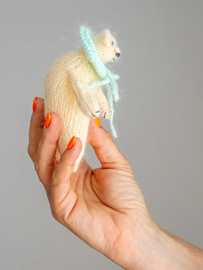 Ottilie The Bear Cashmere Figure , a cashmere bear held by a person against a grey backdrop. 
