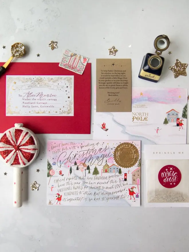 The full pink set: an addressed envelope, a North Pole Post Office card, a Chief Elf note and Magic Dust.