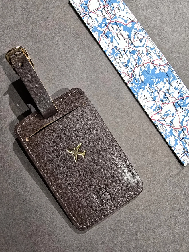 a dark brown leather luggage tag embossed with a gold airplane