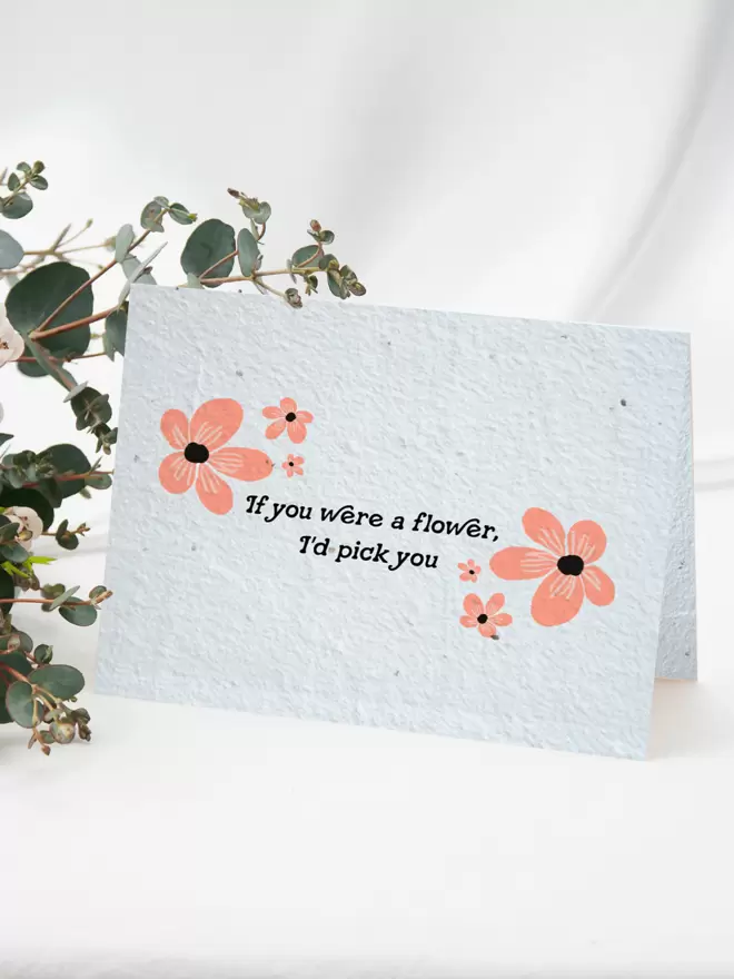 Seeded Paper Greeting Card with ‘If you were a flower I’d pick you’ in the centre with pink floral illustrations with a bunch of flowers in the background