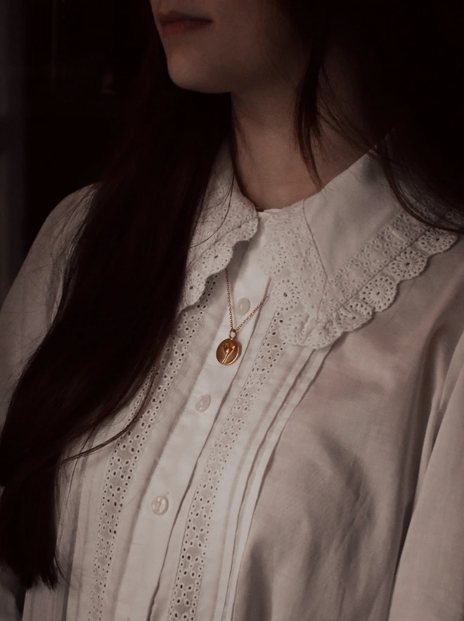 Gold Daisy Coin Charm representing new beginnings in the language of flower worn by a model