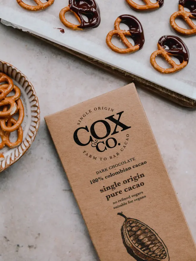 100% Single Pure Cacao Chocolate Bar (Set Of 1, 2 Or 3), a chocolate bar sitting on a table surface. It is surrounded by other chocolate treats. 