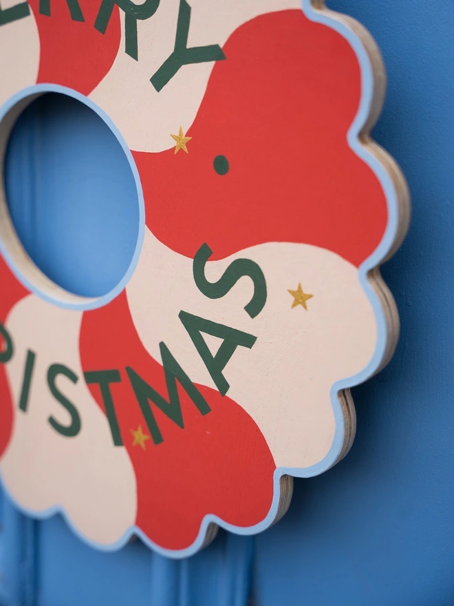 Red and pale pink Hand painted Christmas Wreath with gold leaf stars on a blue front door