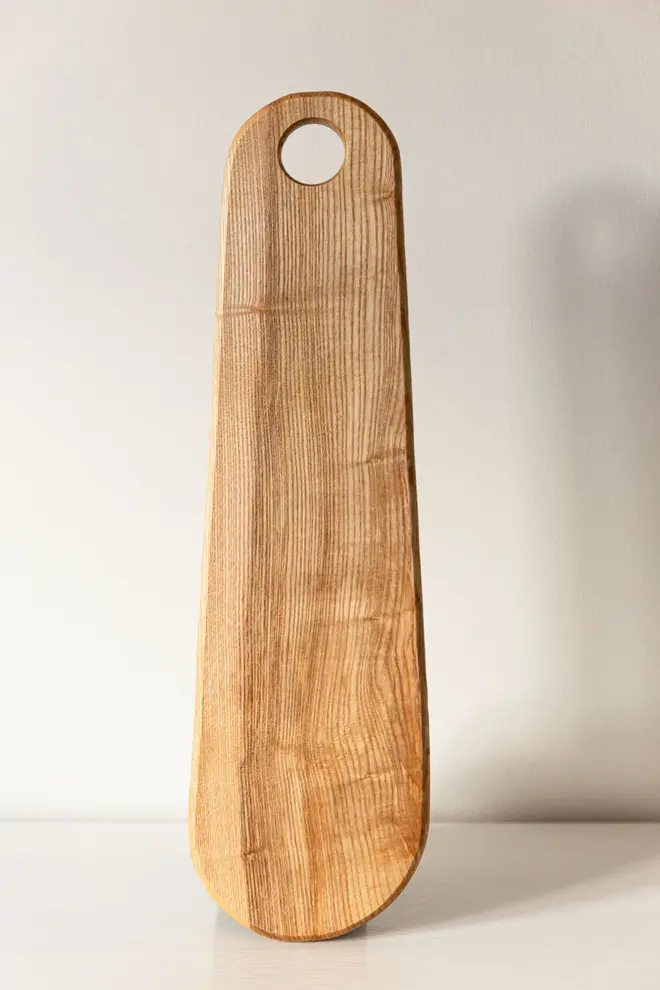 Ash Paddle Serving Board, a wooden serving board sat on a plain surface.