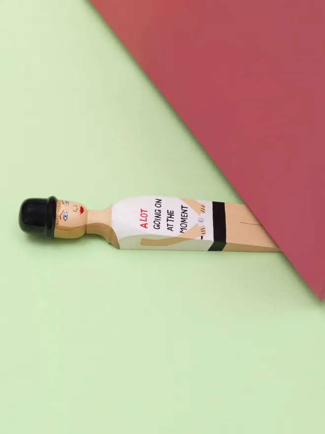 Wooden Door Stopper (Swifty Going On Outfit), a colourful wooden door stop sitting under a door.