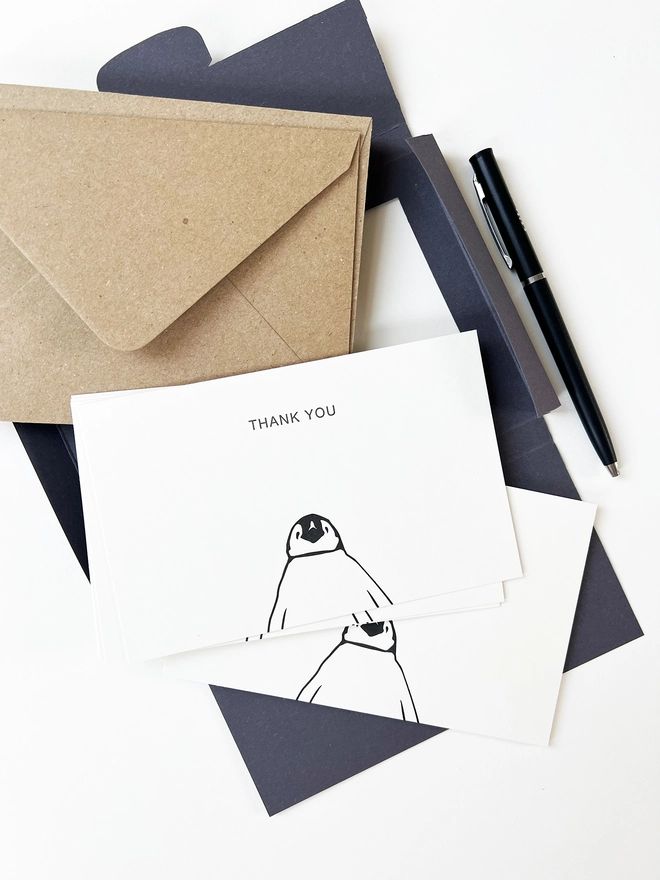 Open box showing the kraft envelopes and penguin cards