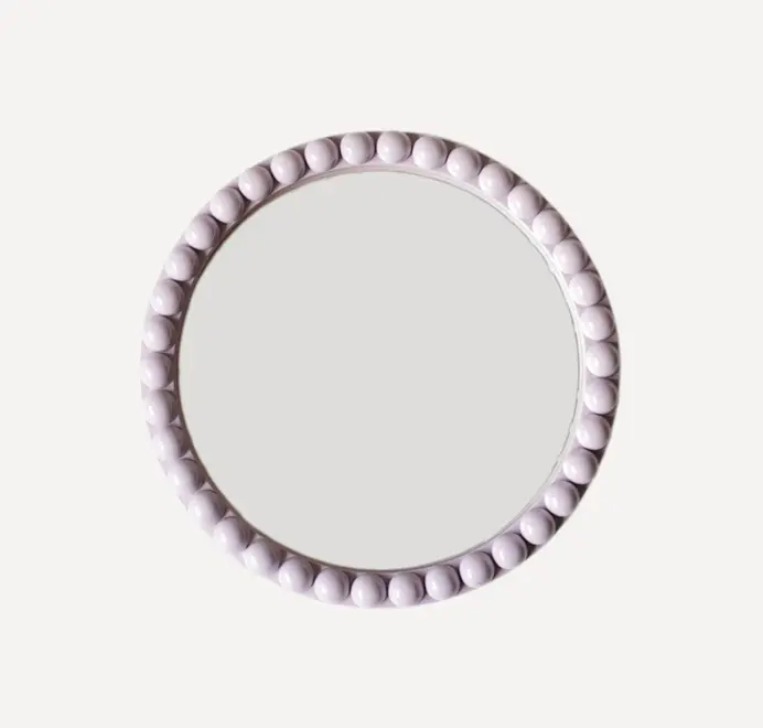 Round oversized bobbin mirror with a decorative bobbin-style wooden frame, hanging on a white wall.