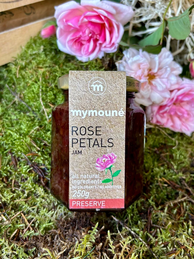 A jar of delicious Rose jam on a bed of moss in front of beautiful pink roses