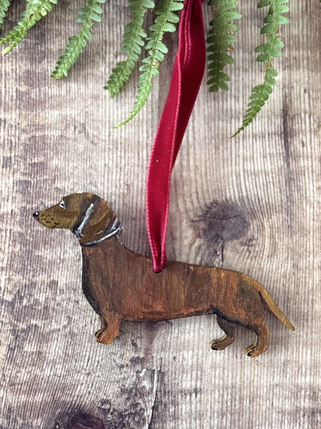 Smooth - haired  tan coloured Wooden dachshund Christmas Decorations strung with red velvet ribbon