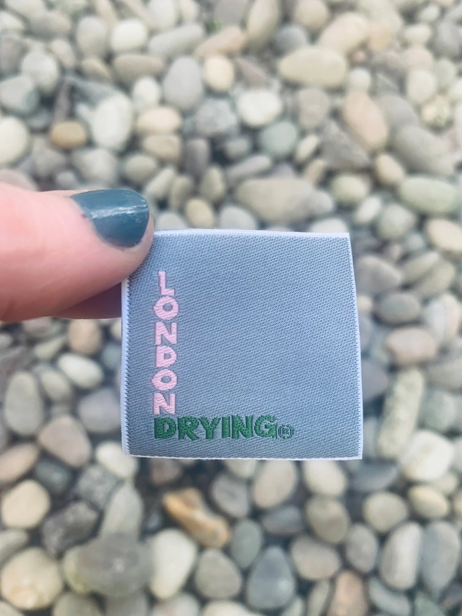 London Drying branded woven label held above gravel