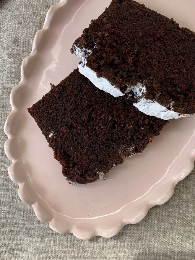 top view of a pale pink oval cake plate with slices of chocolate cake 